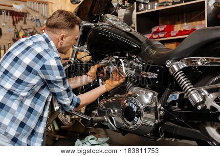 Make it tighter. Industrious to decent specialist tightening a bolt on his lovely vehicle while spending time at his workshop maintaining it