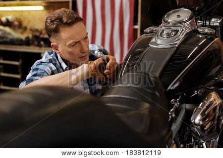 Making another checkup. Hardworking capable industrious man doing some final touches on the bike while repairing it and fulfilling clients order