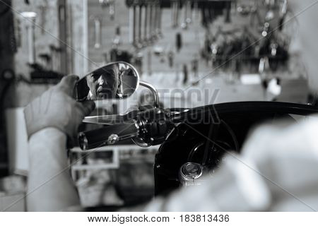 Hitting old roads. Handsome dreamy masculine guy sitting on repaired vehicle and looking in the rearview mirror after fixing it