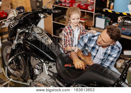 Lovely help. Nice responsible smart daughter helping her dad in the garage while he enjoying his hoppy and renewing a vintage motorbike