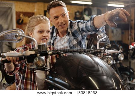 Just imagine a highway. Optimistic creative great dad drawing a picture of the road trip for his daughter while she sitting on a bike and looking dreamy