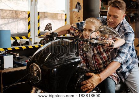 Sit tight. Protective loving handsome father holding a bike and his child while she imagining herself taking a real ride