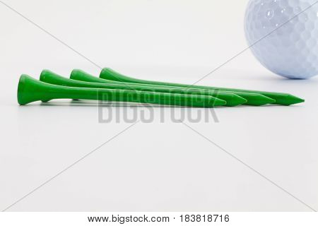 Green wooden golf tees and golf ball on the white table