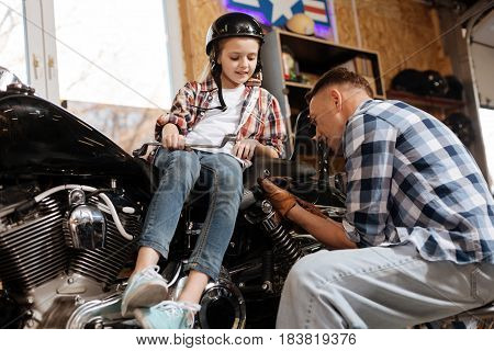 Dad at work. Interested charming curious child trying figuring out what her parent doing while watching his actions with great enthusiasm