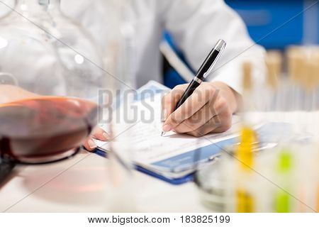 Partial View Of Scientist Writing In Notepad In Laboratory