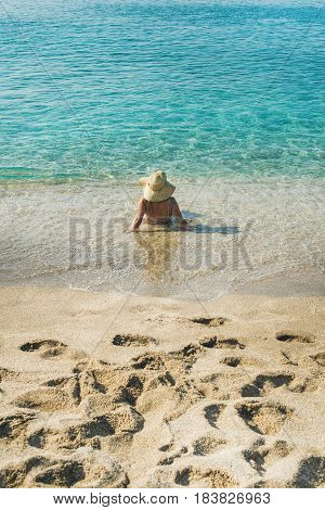 Beautiful slim senior woman tourist in bikini and hat lying on sand enjoying clear sea waters at Meditteranean resort of Turkey in Alanya, Kleopatra beach, rear view
