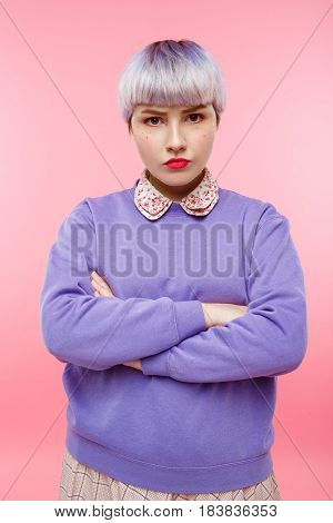 Fashion close-up portrait of confident beautiful dollish girl with short light violet hair wearing lilac sweater over pink background. Copy space.
