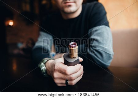 Close-up of electronic cigarette. The man smiles and smokes vape. The concept of refusal of tobacco. Vaping