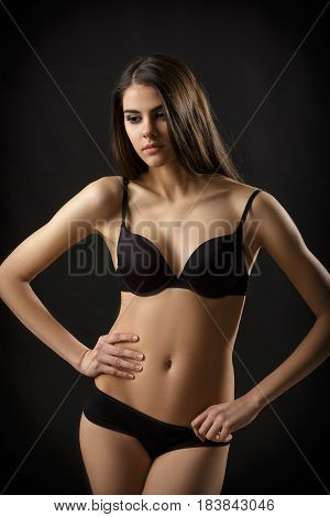 beautiful sexy brunette woman posing in black lingerie on the black background. Seductive and attractive slim shapely body