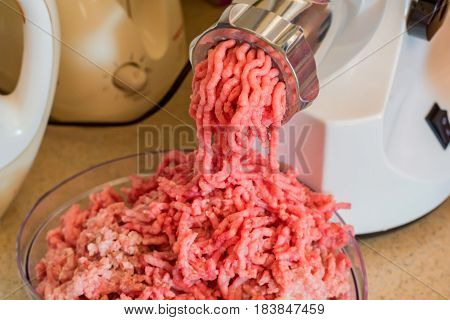 Closeup of minced raw meat coming out from grinder