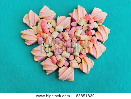 Marshmallows Background or texture of colorful mini marshmallows Multicolored marshmallows are lying in the shape of a heart on a blue background