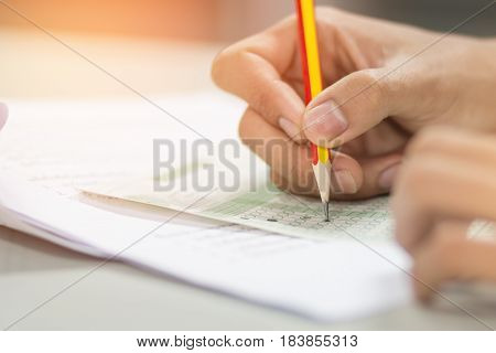 students hand testing doing examination with pencil drawing selected choice on answer sheets in school exam at college