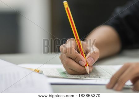 students hand testing doing examination with pencil drawing selected choice on answer sheets in school exam at college