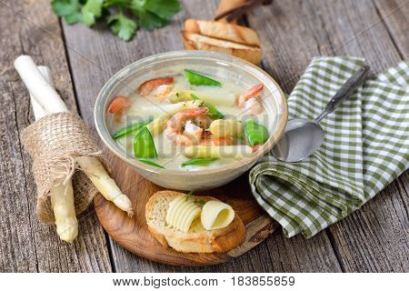 Cream of asparagus soup with fried prawns and snow peas, served with toasted baguette with butter rolls