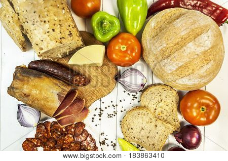 Healthy vegetables and sirloin and sousage on a wooden white table with dietary bread