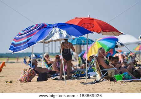 Rehoboth Beach USA - July 30 2013: People resting on beach under umbrellas on sunny summer day in Delaware