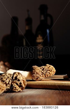 In close-up raw morels and gyromitra mushroom in the rays of sunlight on the dark background