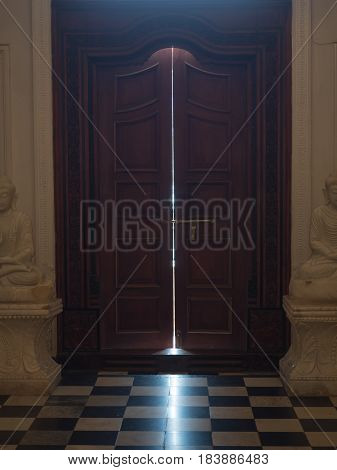 Slightly opened door in the church with light coming through.