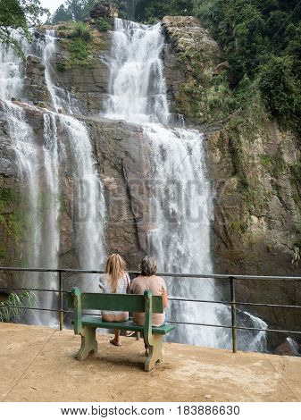 Girls on the bench near waterfall, sri lanka