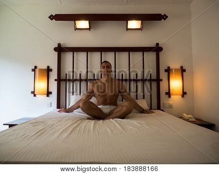 Young man relaxing yoga in bed after waking up in the morning.