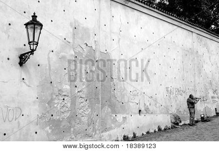 Unidentified street musician standing near the wall and playing on violin in Prague, Czech Republic (monochrome).