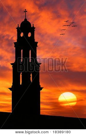 Vertical oriented image of the old church silhouette on beautiful sunset sky with red clouds and sun in Yafo, Israel.
