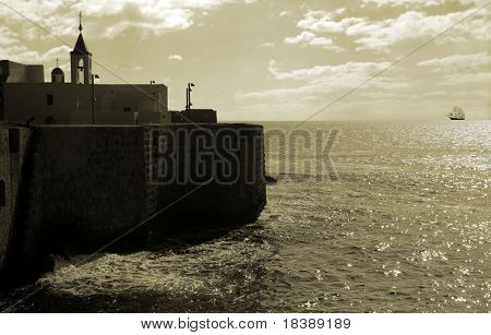 Walls and church of ancient fortress on Mediterranean Sea in Acre, Israel (sepia toned).
