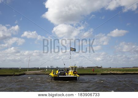 Eemdijk, the Netherlands - march 3, 2016; Yellow ferry is crossing the river Eem at Eemdijk, the Netherlands