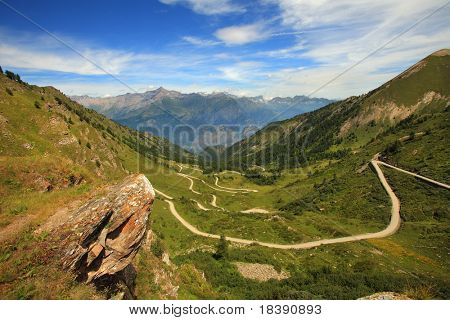 Mostra sulla strada sterrata che attraversa la valle nelle Alpi, Italia.