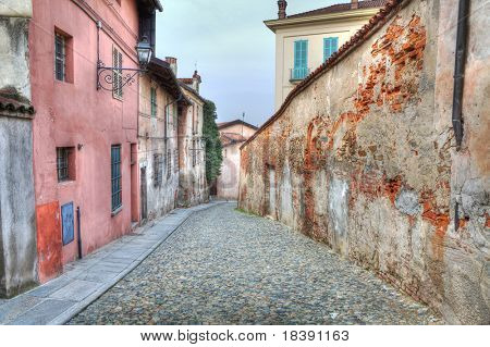 Schmalen gepflasterten Straße zwischen den alten Häusern und alten Mauer in Saluzzo, Norditalien.