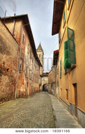 vertikal ausgerichtete Bild des engen gepflasterten Straße zwischen alten historischen Häusern im Saluzzo, Italien.