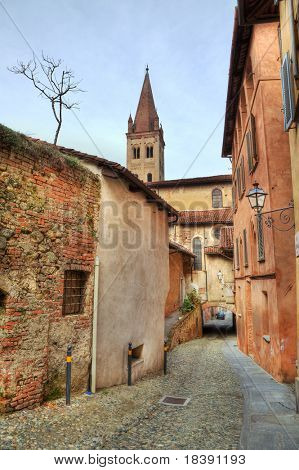 vertikal ausgerichtete Bild des engen gepflasterten Straße zwischen alten historischen Häusern im Saluzzo, Italien.