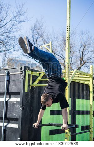 Young Athlete doing a Hand Stand On Parallel Bars In An Outdoor Gym - Street Workout Exercises. Man's flexibility.