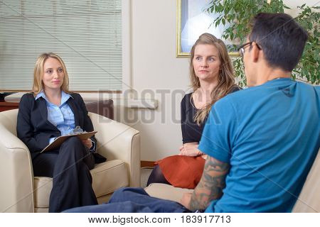 Young couple talking to therapist. Attractive ellegant woman listening attentively, taking notes.