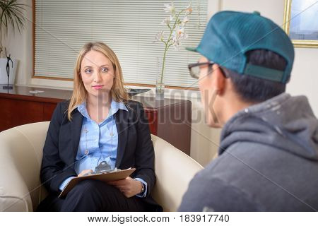 Therapist talking to patient. Young attractive ellegant woman listening attentively, taking notes.