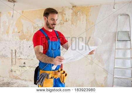 Handyman watchig blueprnts of home renovations success job