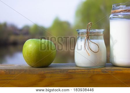 Milk kefir in glass with green apple on river photographed with natural light