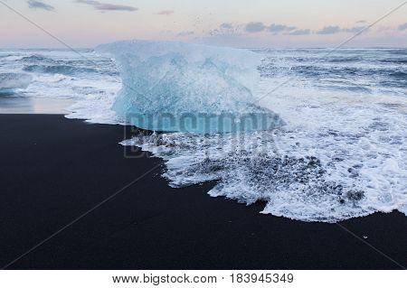 Ice cube breaking on black sand beach Iceland winter season lanscape background