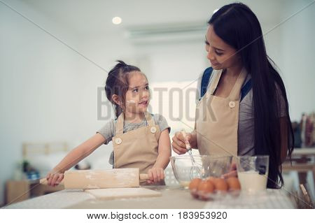 mother and daugthter cooking togather for make bread for dinner in kitchen room kid children