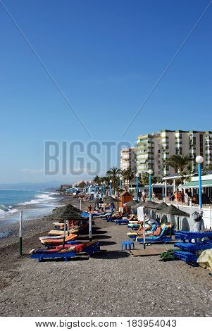 TORROX COSTA, SPAIN - OCTOBER 27, 2008 - Tourists relaxing on the beach with the promenade and apartments to the rear Torrox Costa Malaga Province Andalusia Spain Western Europe, October 27, 2008.