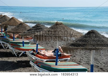 TORROX COSTA, SPAIN - OCTOBER 27, 2008 - Tourists relaxing on the beach with views across the sea Torrox Costa Malaga Province Andalusia Spain Western Europe, October 27, 2008.