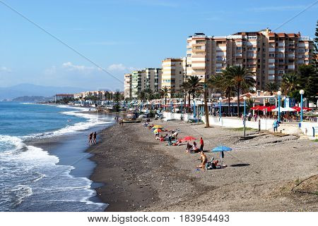 TORROX COSTA, SPAIN - OCTOBER 27, 2008 - Tourists relaxing on the beach with the promenade and apartments to the rear Torrox Costa Malaga Province Andalusia Spain Western Europe, October 27, 2008.