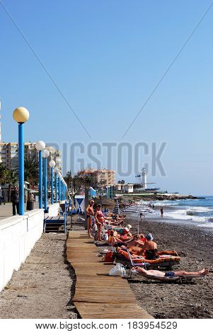 TORROX COSTA, SPAIN - OCTOBER 27, 2008 -Tourists relaxing on the beach with the promenade and apartments to the rear Torrox Costa Malaga Province Andalusia Spain Western Europe, October 27, 2008.