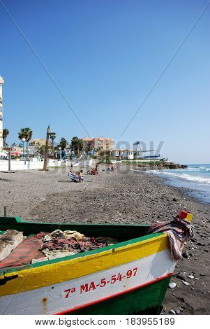 TORROX COSTA, SPAIN - OCTOBER 27, 2008 - Traditional wooden fishing boat on the beach with tourists to the rear Torrox Costa Malaga Province Andalusia Spain Western Europe, October 27, 2008.