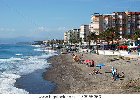 TORROX COSTA, SPAIN - OCTOBER 27, 2008 - Tourists relaxing on the beach with the promenade and apartments to the rear Torrox Costa Malaga Province Andalusia Spain Western Europe, October 27, 2008.