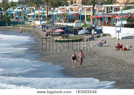 TORROX COSTA, SPAIN - OCTOBER 27, 2008 -Tourists relaxing on the beach with the promenade and apartments to the rear Torrox Costa Malaga Province Andalusia Spain Western Europe, October 27, 2008.