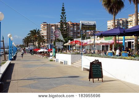 TORROX COSTA, SPAIN - OCTOBER 27, 2008 -Tourists walking along the promenade with pavement cafes to the right hand side Torrox Costa Malaga Province Andalusia Spain Western Europe, October 27, 2008.