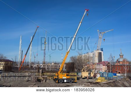 Construction of houses on the river Bank. A lot of tower cranes in the shot against the sky. The process of construction.