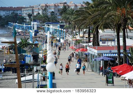 TORROX COSTA, SPAIN - OCTOBER 27, 2008 - Tourists walking along the promenade with pavement cafes to the right hand side and the beach to the left Torrox Costa Malaga Province Andalusia Spain Western Europe, October 27, 2008.
