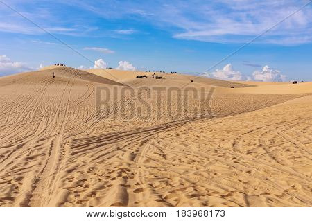Sand dunes near Mui Ne. Group of off roads on top of dunes in the background. Sunny day with blue sky and clouds. Sand dune at Mui Ne Vietnam